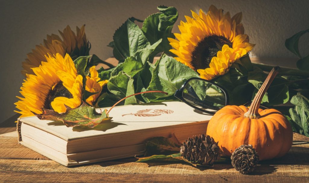 Sunflowers, book, and pumpkin on a rustic table.